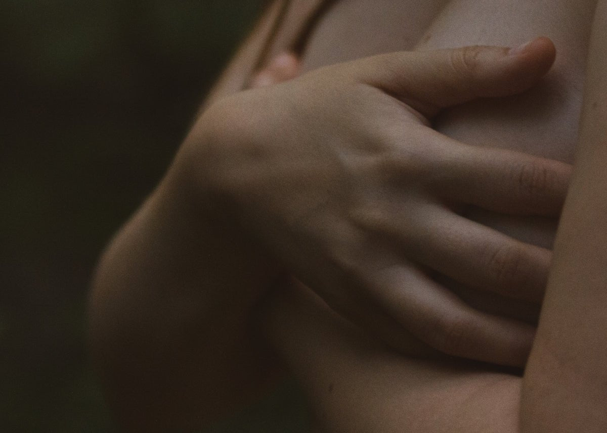 a close up of a woman's breast with her hands on her chest